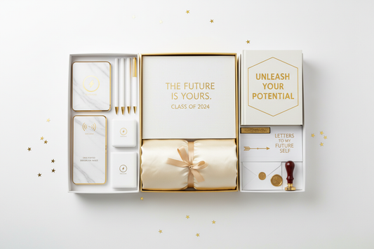 High school graduation gift box flat lay with planner, silk pillowcase, tech accessories, motivational book and letters to future self kit